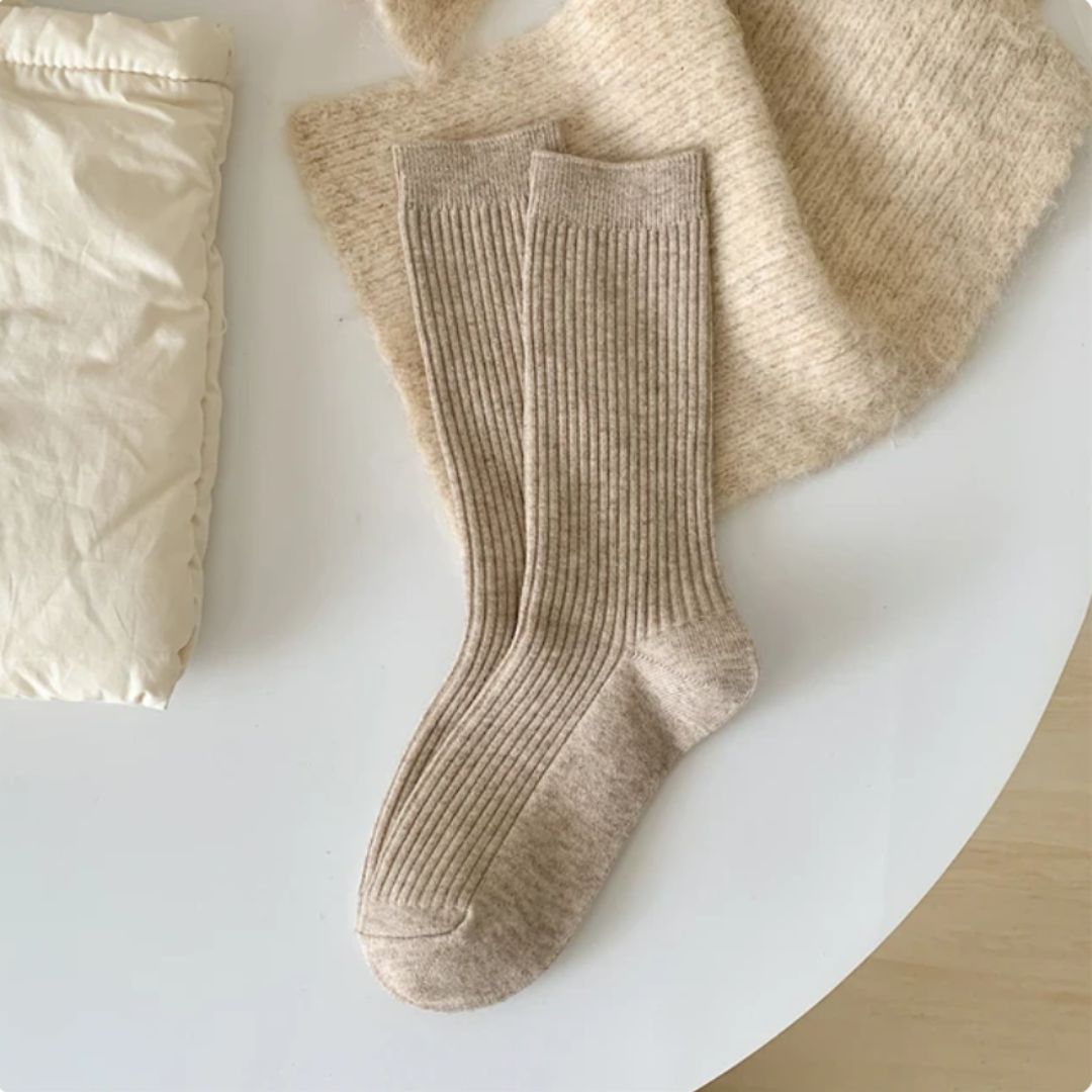 Beige Wollsocken auf weißem Tisch, gestricktes Design, gemütlich, warm, Wintermode Accessoire.
