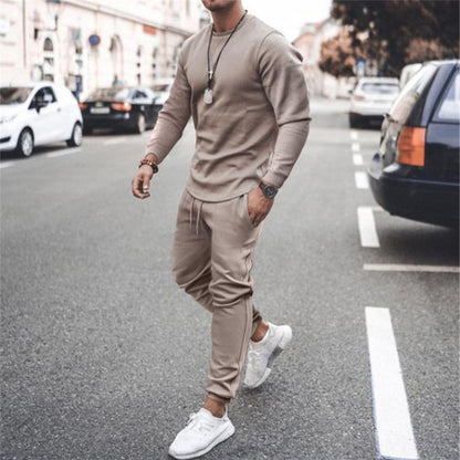 Mann in beigem Trainingsanzug und weißen Sneakers auf Straße, modische Freizeitkleidung.