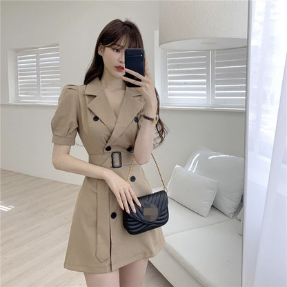 Frau in beigem Trenchcoat-Kleid mit schwarzer Umhängetasche, modernes Wohnzimmer.