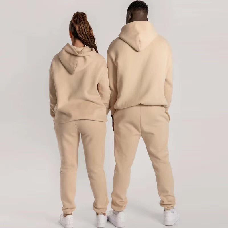 Zwei Personen in beigen Jogginganzügen aus Fleece, Kapuzenpullover und Jogginghose, Rückansicht.