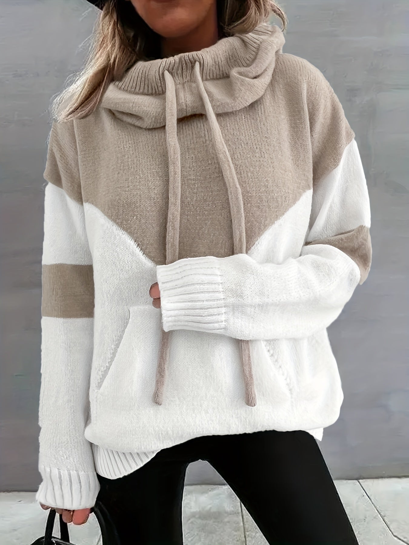 Frau in beige-weißem Strickpullover mit Kapuze, Kordeln und Taschen, modisch, gemütlich.