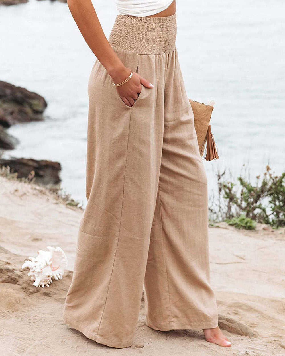 Frau in beige Leinenhose am Strand, hoch tailliert, Sommermode, lässig, bequem.