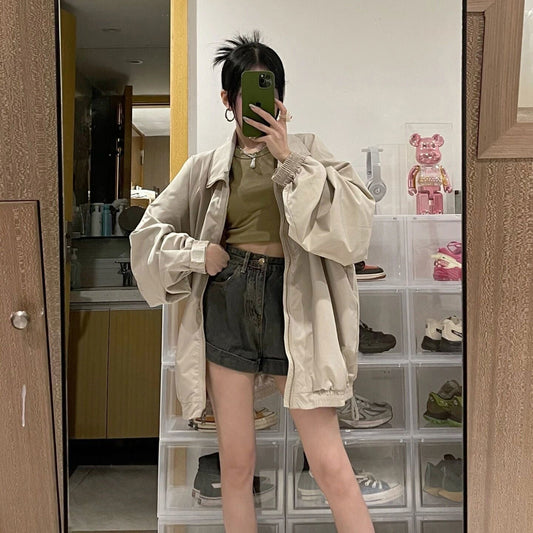 Frau in beiger Jacke und Jeansshorts, Spiegel-Selfie, modisch, lässiger Stil, modernes Outfit.