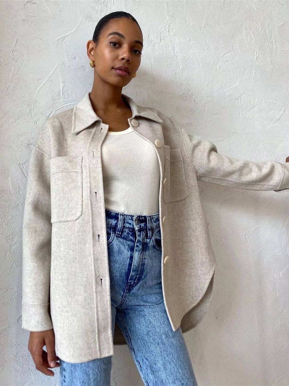 Frau in beiger Wolljacke, weiße Bluse, blaue Jeans, lässiger Look, Mode, Damenbekleidung.