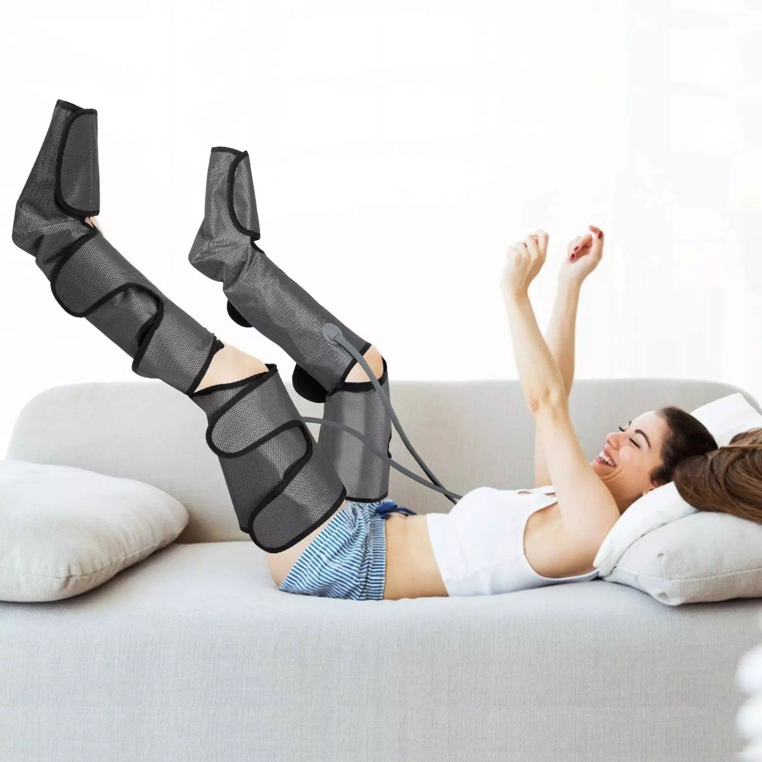 Frau mit Beinmassagegerät, schwarz, auf Sofa, Entspannung, Kompressionsstiefel, Erholung.
