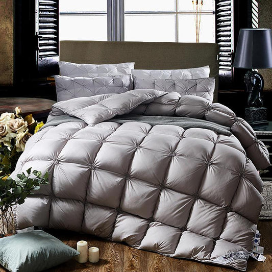 Luxuriöse graue Steppbettdecke auf Bett mit Kissen, ideal für gemütliches Schlafzimmerambiente.