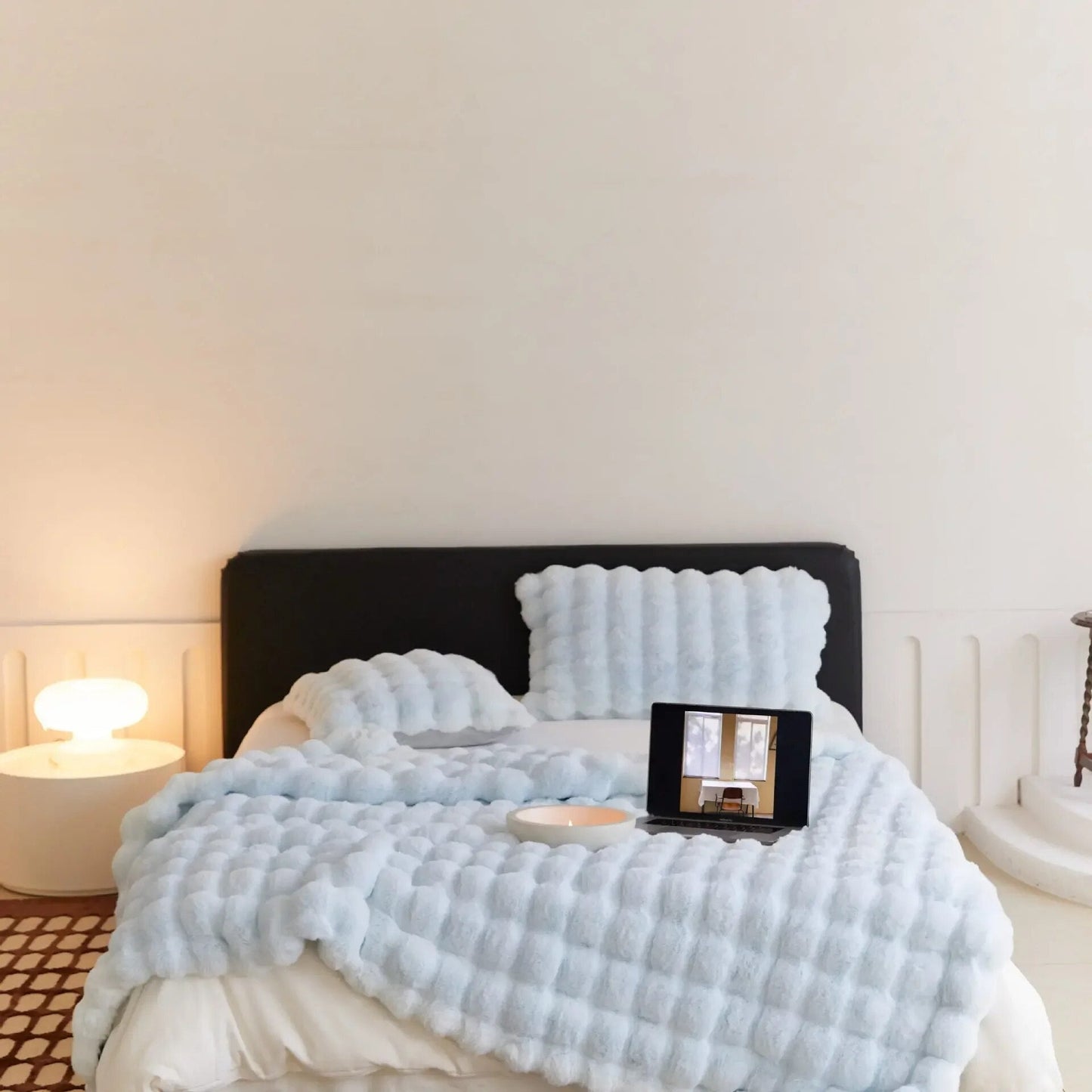 Gemütliches Schlafzimmer mit blauem Bettüberwurf, Tablet auf Bett, moderne Nachttischlampe.