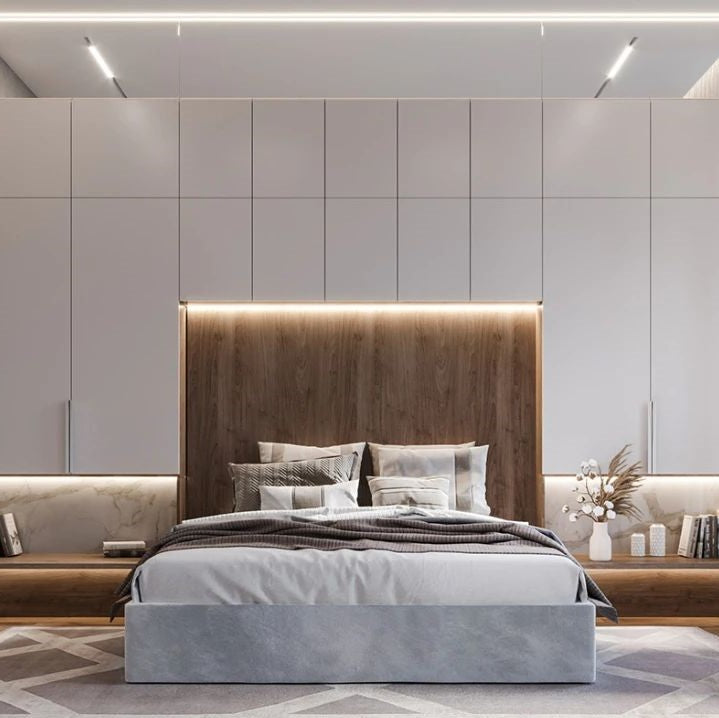 Modernes Schlafzimmer mit grauem Bett, Holzrückwand, weißen Schränken und LED-Beleuchtung.