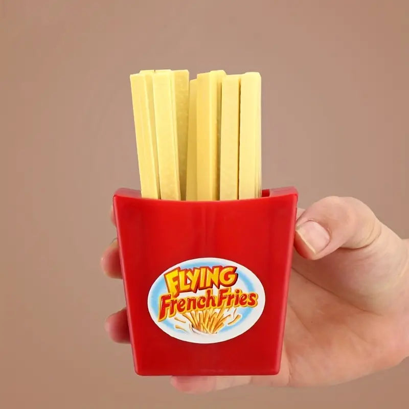 Rote Pommes-Frites-Box mit gelben Spielzeugstäbchen, Hand hält Box, lustiges Design.
