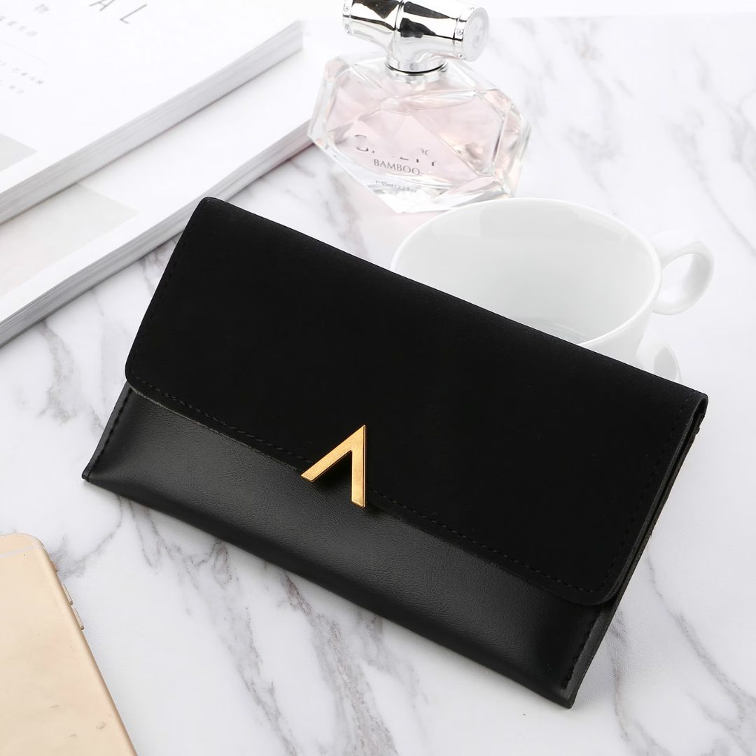 Schwarze Lederhandtasche mit goldener Schnalle auf Marmortisch, elegantes Damenaccessoire.
