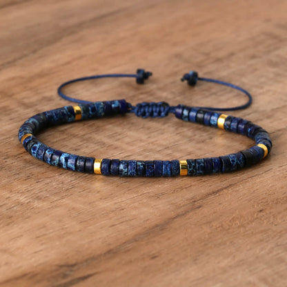 Blaues Armband mit goldenen Akzenten, verstellbar, handgefertigt, auf Holztisch.