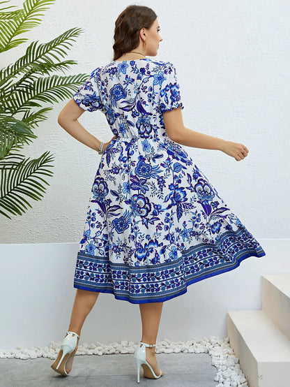 Frau in blau-weißem Blumenkleid, knielang, Sommermode, elegante Sandalen, Rückansicht.