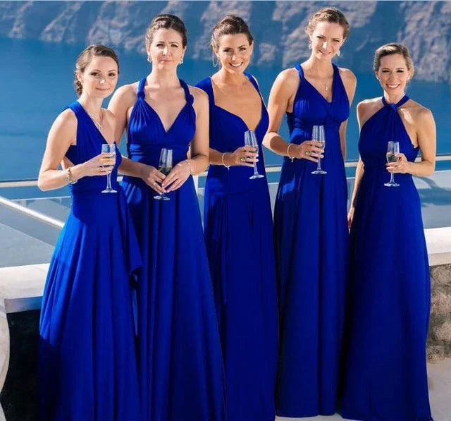 Fünf Frauen in blauen Abendkleidern mit Sektgläsern vor Meerblick.
