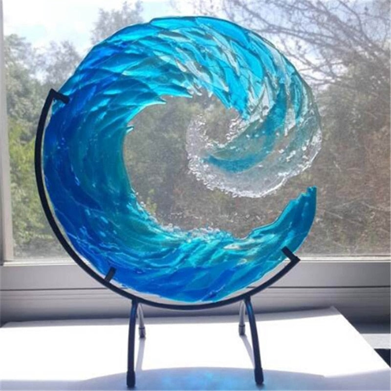 Blaue Glaswelle Skulptur auf schwarzem Ständer, dekorative Kunst für Zuhause, Fensterhintergrund.