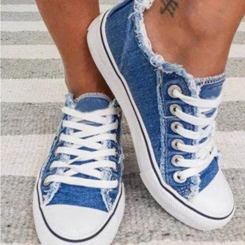 Blaue Jeans-Sneaker mit weißen Schnürsenkeln, lässige Damenmode, Straßenschuhe.