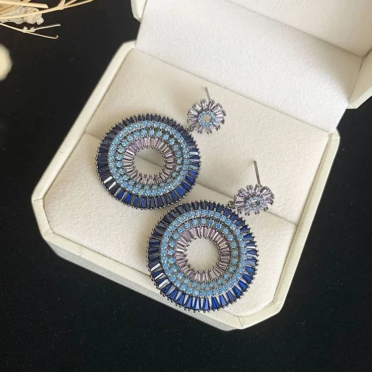 Blaue runde Ohrringe mit Kristallen in Schmuckschatulle, elegantes Design, Damenaccessoire.