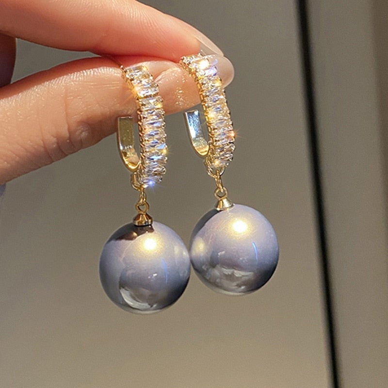 Goldene Ohrringe mit blauen Perlen und Kristallen, eleganter Schmuck für Damen.