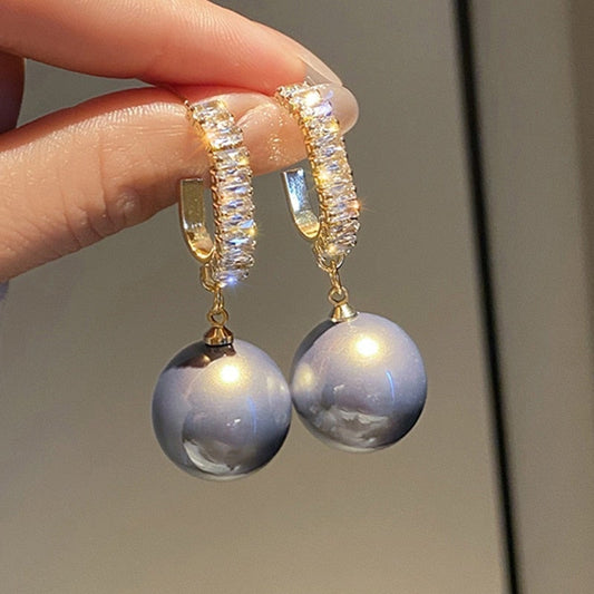 Goldene Ohrringe mit blauen Perlen und Kristallen, eleganter Schmuck für Damen.
