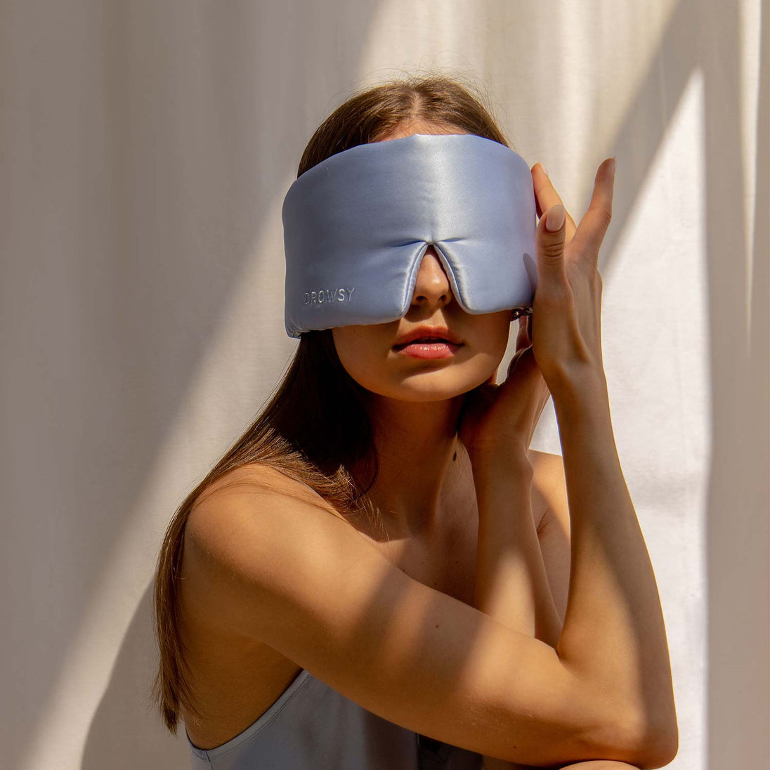 Frau trägt blaue Seidenschlafmaske, Drowsy, für besseren Schlaf, luxuriös, bequem.