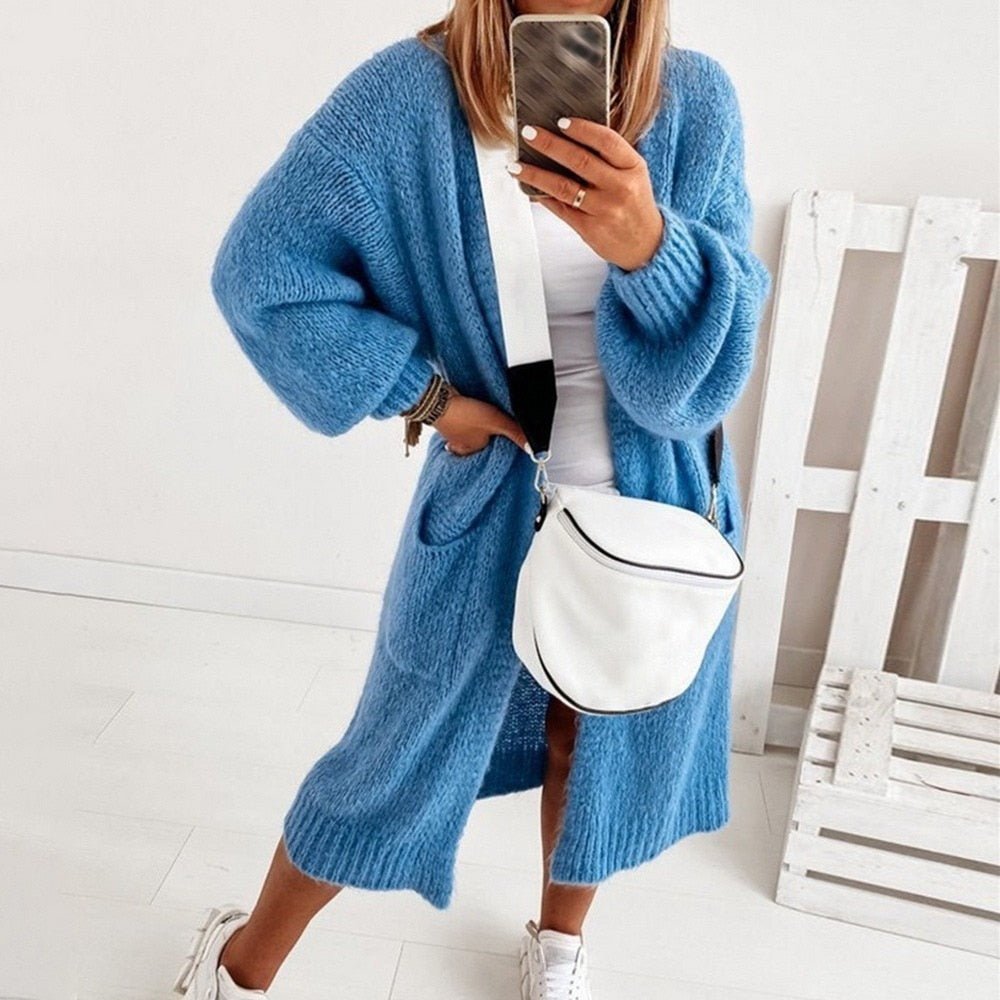 Frau in blauer Strickjacke, weißem Top und Sneakers, modisch, bequem, lässiger Stil.