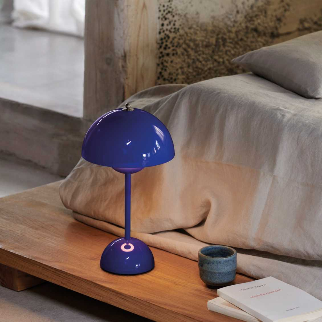 Blaue Tischlampe auf Holztisch neben Bett, modernes Design, Schlafzimmerdekoration.