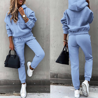 Frau in hellblauem Jogginganzug, weiße Sneaker, schwarze Handtasche, lässiger Stil.