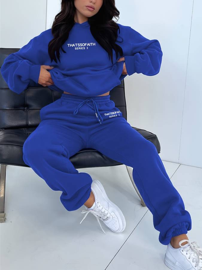 Frau in blauem Hoodie und Jogginghose, weiße Sneaker, moderne Freizeitmode, bequemes Outfit.