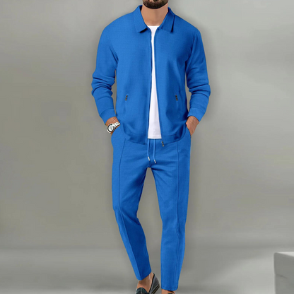 Mann in blauem Anzug mit Reißverschlussjacke und Hose, weißes T-Shirt, lässiger Stil.