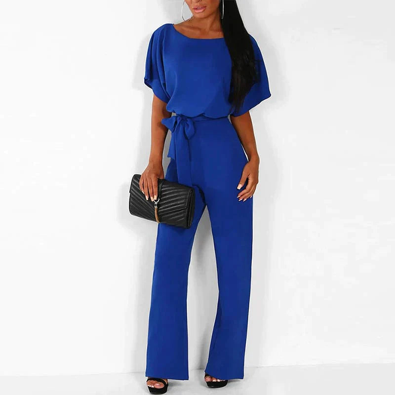 Frau in blauem Jumpsuit mit schwarzer Clutch, elegantes Outfit, Mode für Damen.