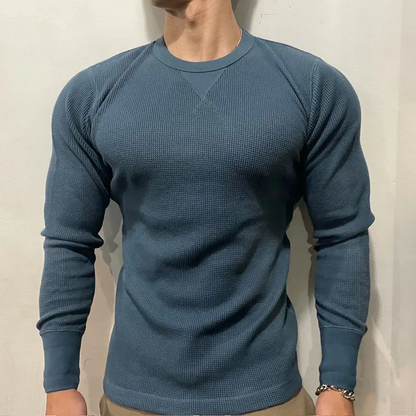 Mann in blauem Langarmshirt, Strickmuster, sportlich, modisch, Herrenbekleidung, Freizeitlook.