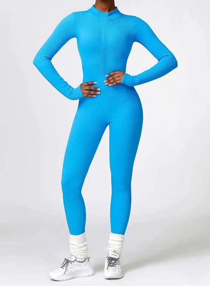 Frau in blauem, nahtlosem Sportanzug, Langarm, Ganzkörper, Fitnessmode, vor grauem Hintergrund.