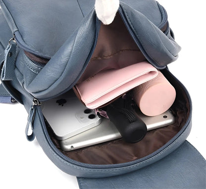 Blauer Lederrucksack mit geöffnetem Fach, zeigt Smartphone, rosa Geldbörse und Flasche.