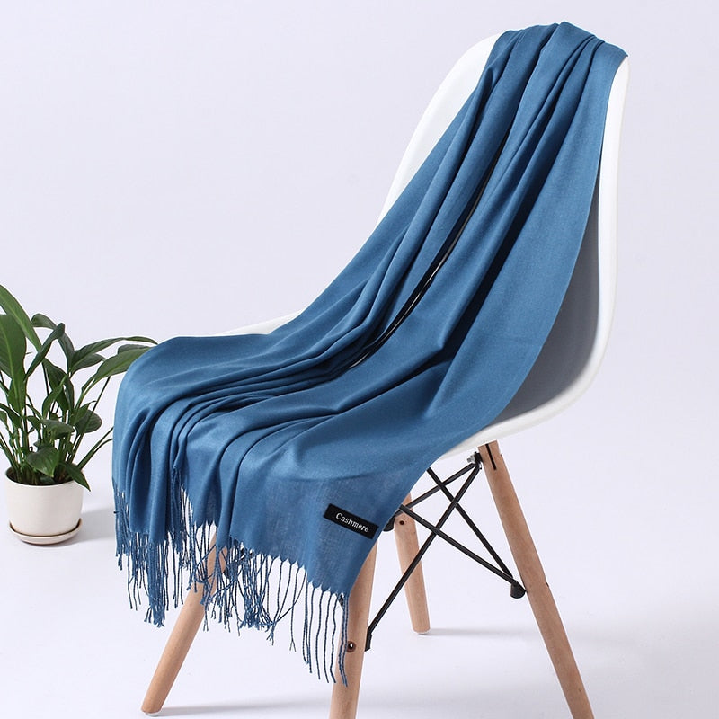 Blauer Kaschmirschal auf Stuhl, weiches Material, modisches Accessoire, Fransen, luxuriös.