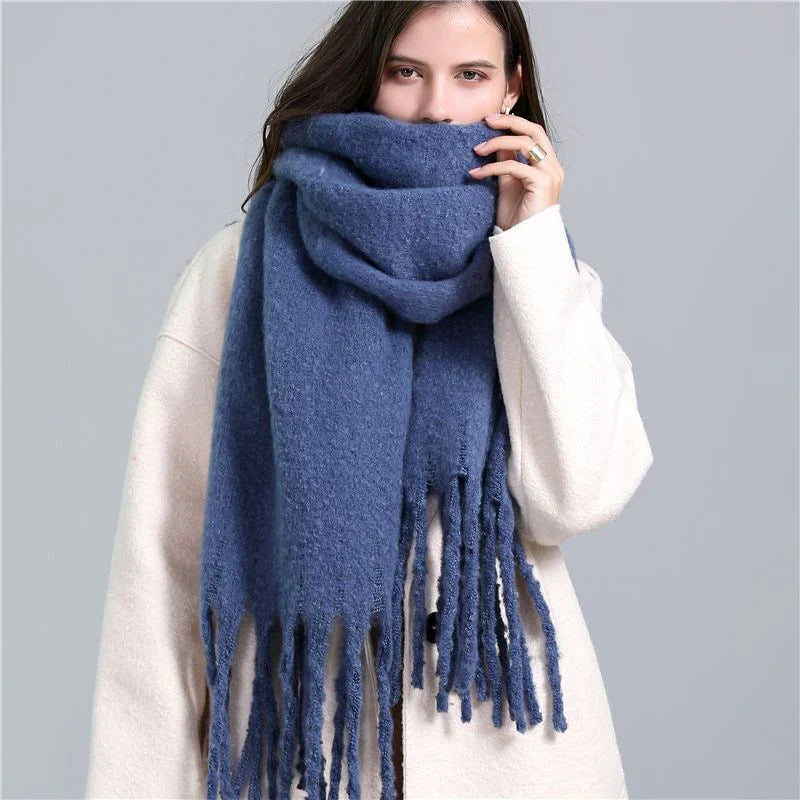 Frau mit blauem Wollschal und weißem Mantel, modisches Winteroutfit, warme Accessoires.
