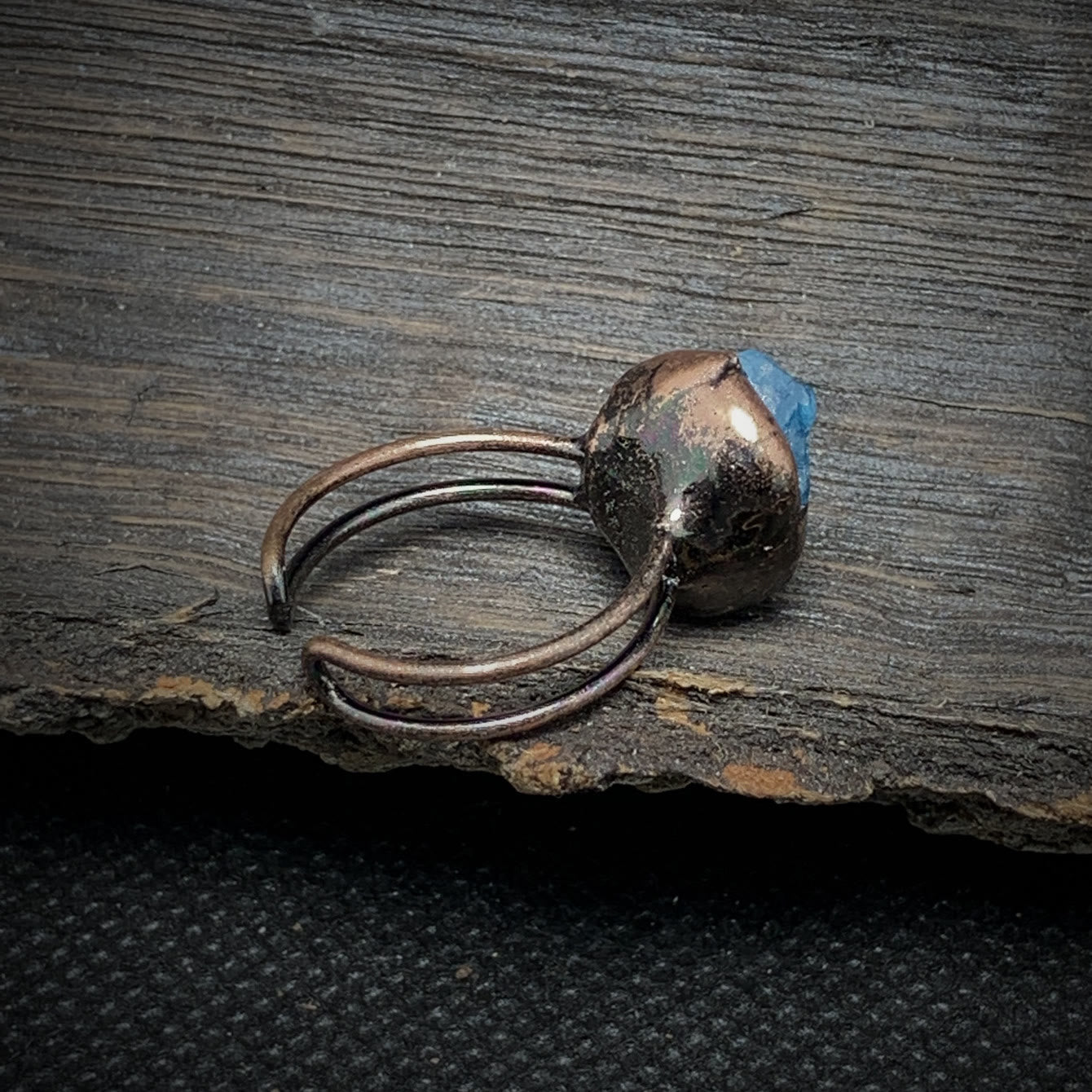 Antiker Kupferring mit blauem Edelstein auf rustikalem Holz, handgefertigter Schmuck.