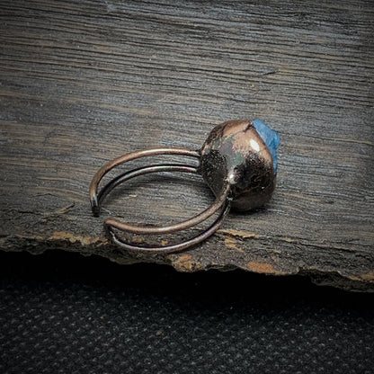 Antiker Kupferring mit blauem Edelstein auf rustikalem Holz, handgefertigter Schmuck.