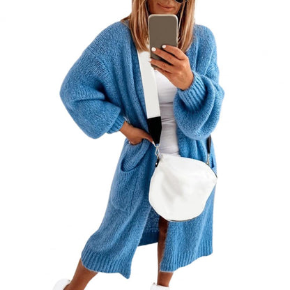 Frau in blauem Strickcardigan mit weißer Umhängetasche, Selfie, modisch, lässig.
