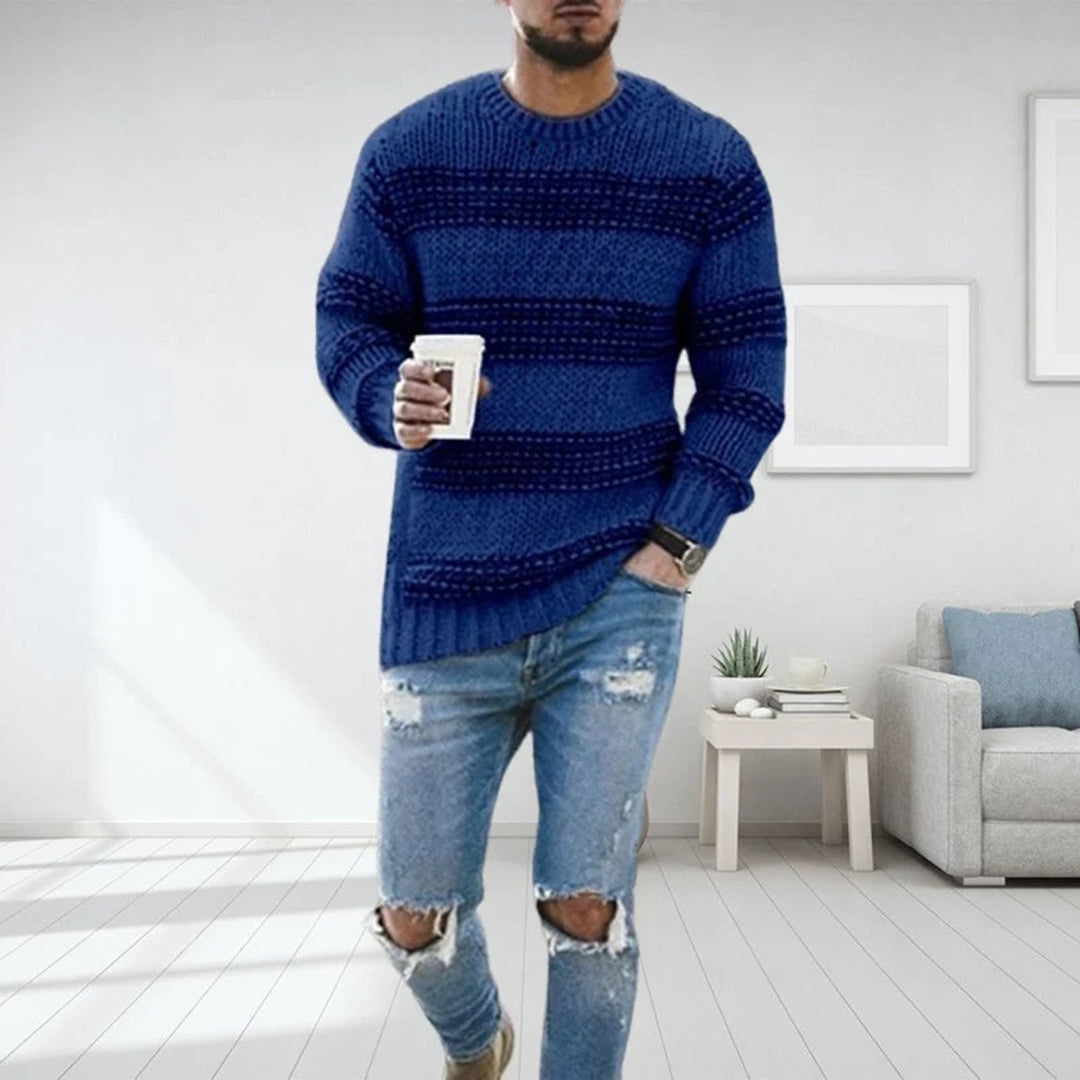 Mann im blauen Strickpullover, zerrissene Jeans, Kaffeetasse, modernes Wohnzimmer.