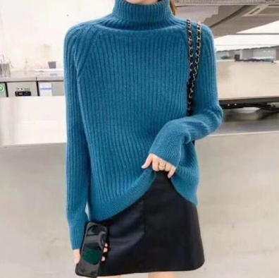 Frau in blauem Rollkragenpullover, schwarzem Rock, hält Smartphone, modisch, Winterkleidung.