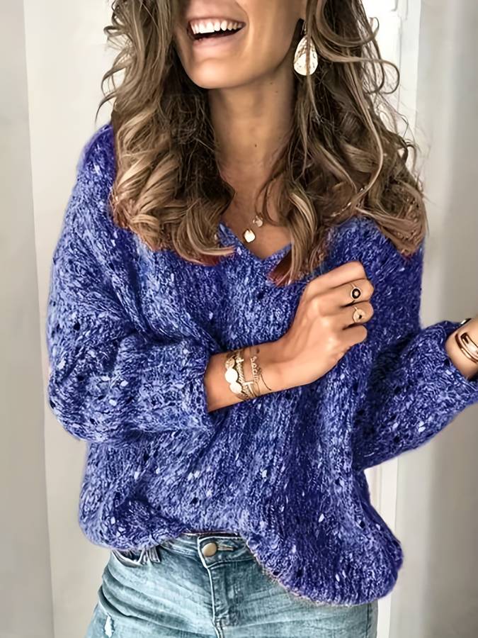 Frau in blauem Strickpullover, lächelnd, mit Schmuck und Jeans, modisch, lässig.