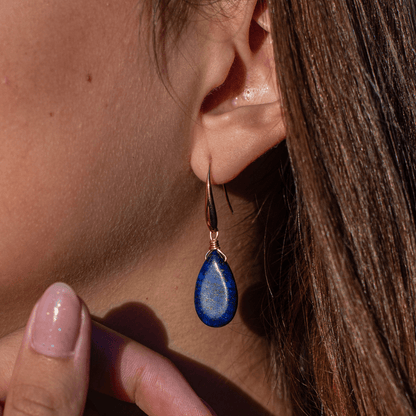 Ohrring mit blauem Tropfen-Anhänger, goldener Haken, eleganter Schmuck, Nahaufnahme.