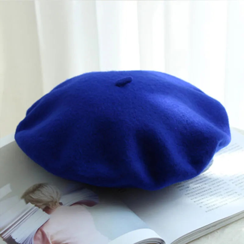Blaue Woll-Baskenmütze auf offenem Buch, stilvolles Accessoire, modisch, elegant.