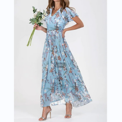 Frau in blauem, geblümtem Maxikleid mit Blumenstrauß, elegante Sommermode.