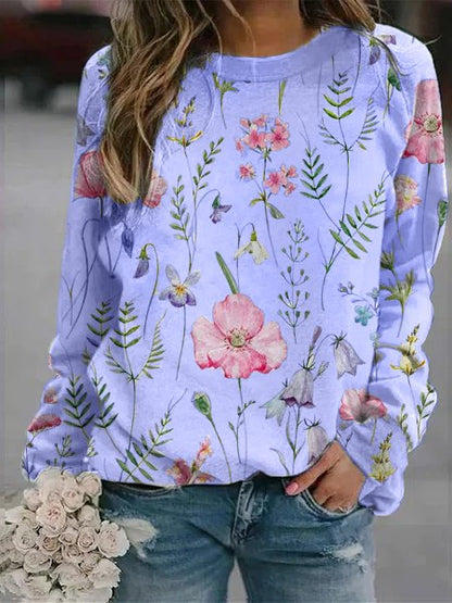 Frau in blauer Blumenpullover, Jeans, hält weißen Blumenstrauß, modisch, lässig.