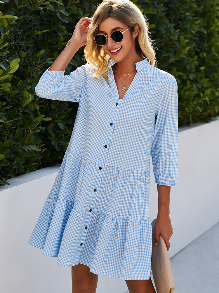 Frau in blau-weiß kariertem Hemdkleid, Sonnenbrille, lächelnd, Sommermode, draußen.