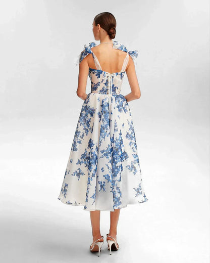Frau im eleganten blauen Blumenkleid, ärmellos, knielang, Sommermode, Rückansicht.