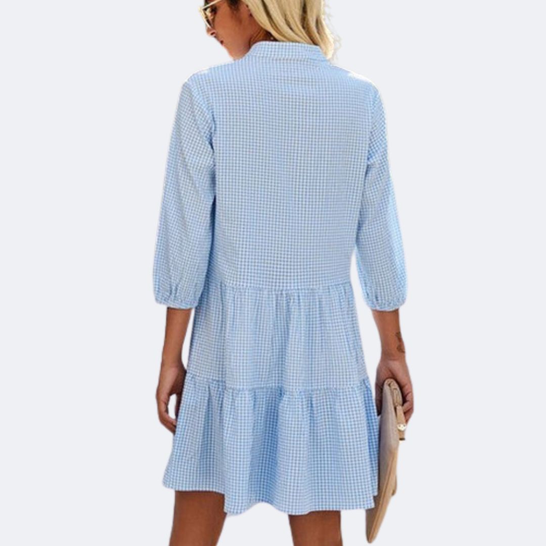 Frau in blau-weiß kariertem Kleid mit langen Ärmeln, Sommermode, Rückansicht.