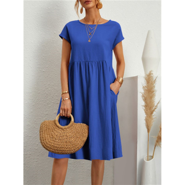Frau in blauem Baumwoll-Leinen-Kleid, Boho-Stil, mit Strohtasche, Sommermode.
