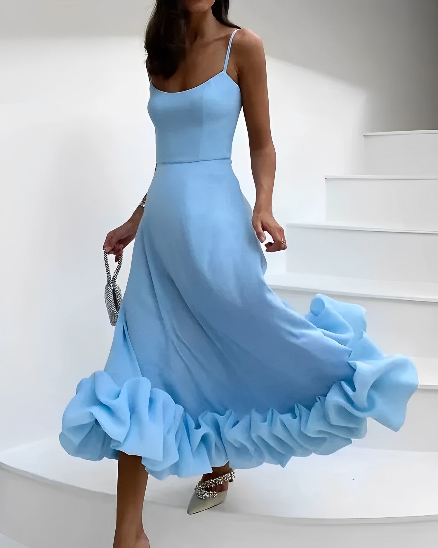Frau in hellblauem Abendkleid mit Rüschen, silberne Clutch, elegante Mode, Treppe.