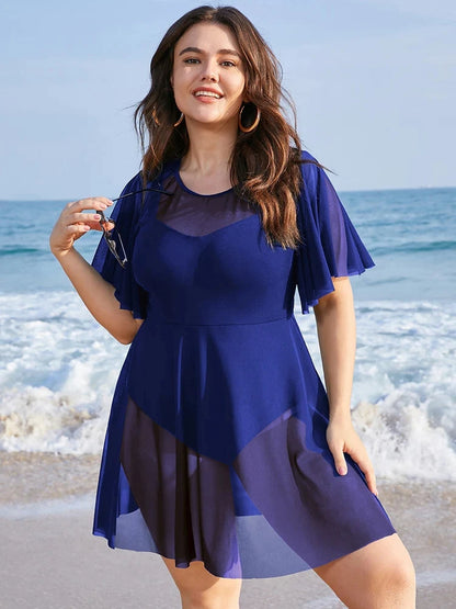 Frau im blauen Sommerkleid am Strand, Plus-Size-Mode, Meereshintergrund, lächelnd.